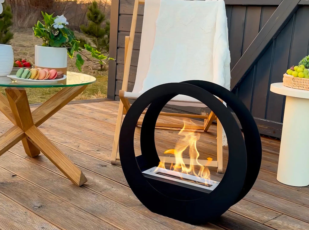 ONLY black bioethanol fireplace burning on wooden decking beside a folding table and reclining chair
