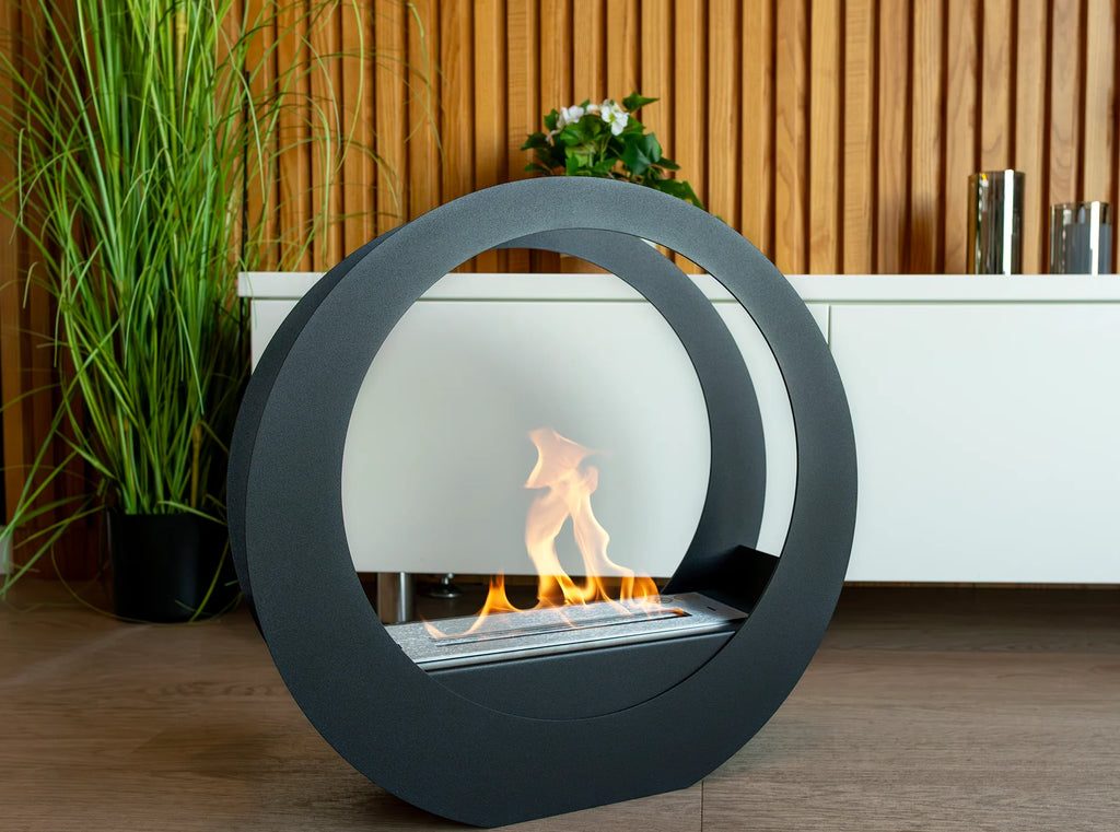 ONLY matt black circular bioethanol fireplace with a lit flame in front of a white cabinet and wooden slat wall